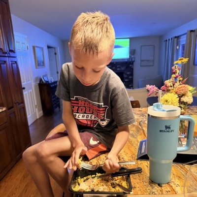 A boy mid-bite of a Strong Kitchen Greek Feta Chicken meal